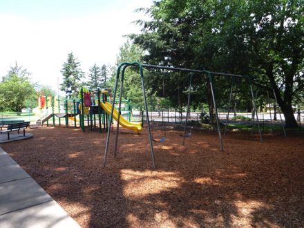 Playground has bark-chip footing – paved pathway through the park has benches – playground is partially fenced